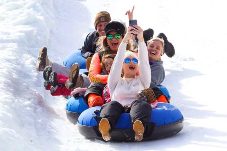 Family laughing on snow tubes