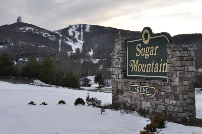 Sugar Mountain Skiing stone sign with snowy ski slopes behind